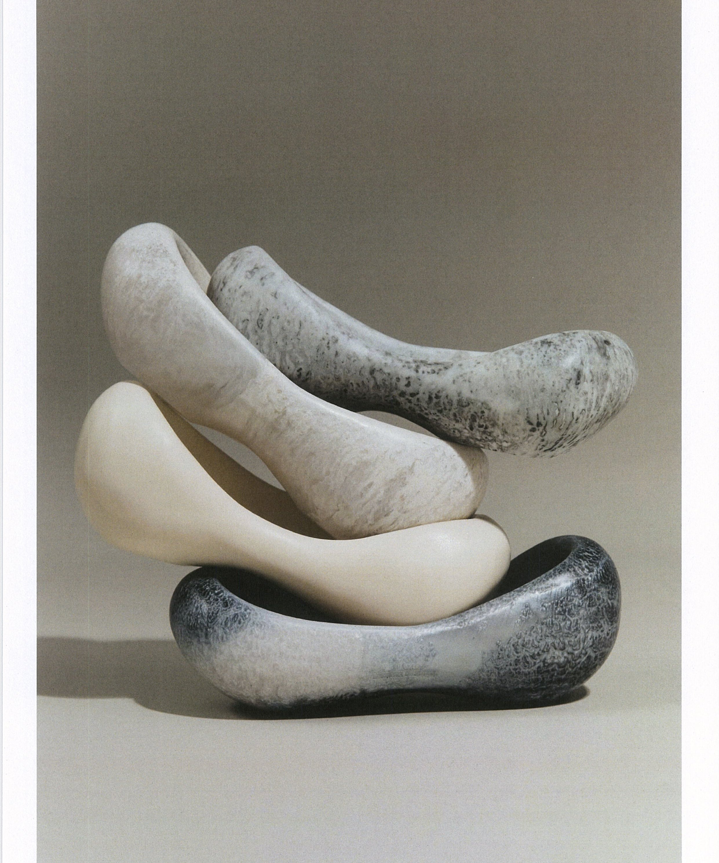 Stack of resin side bowls in various shapes and grey tones on a neutral background