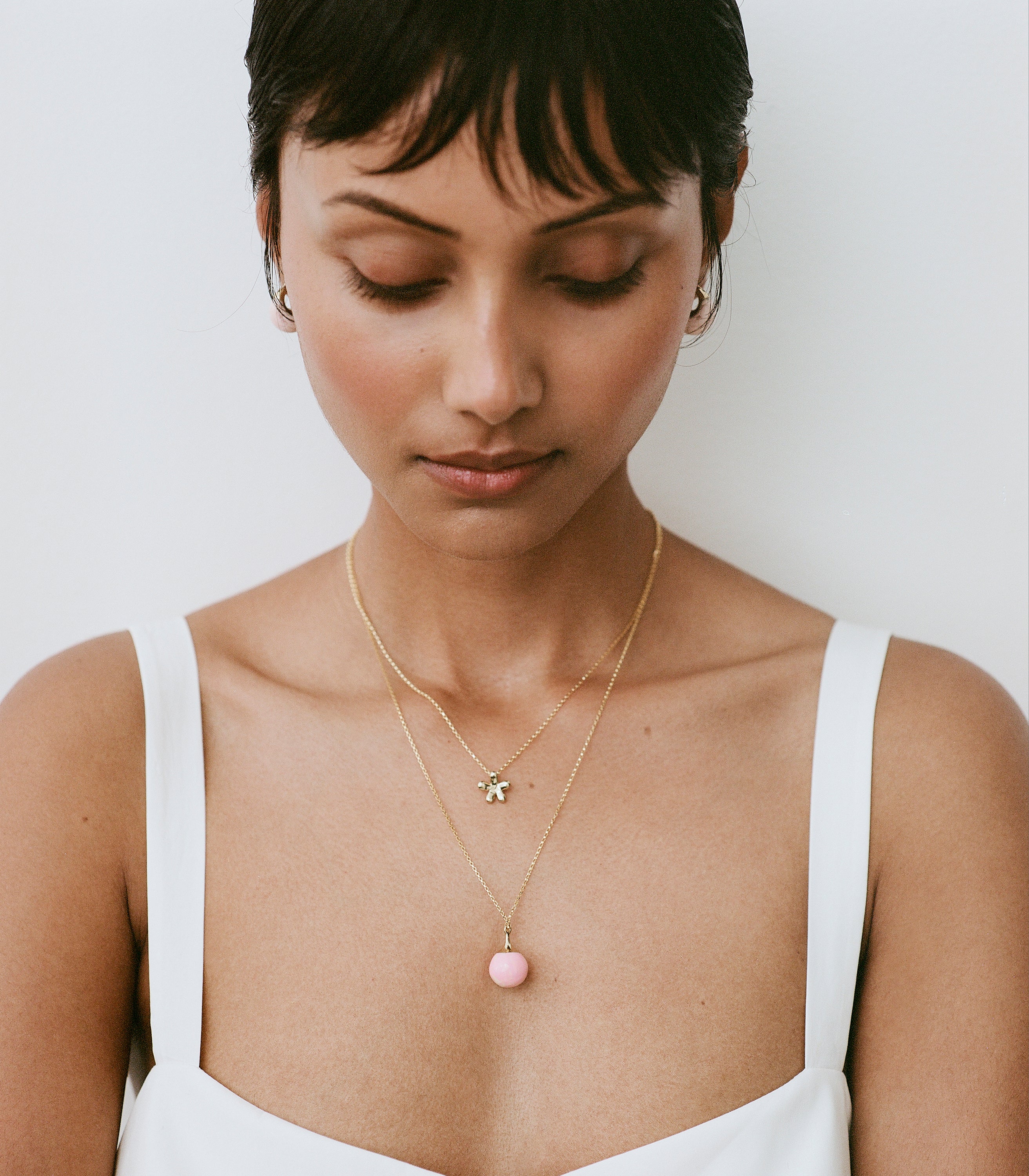 Model wearing brass pendant with pink ball pendant accent