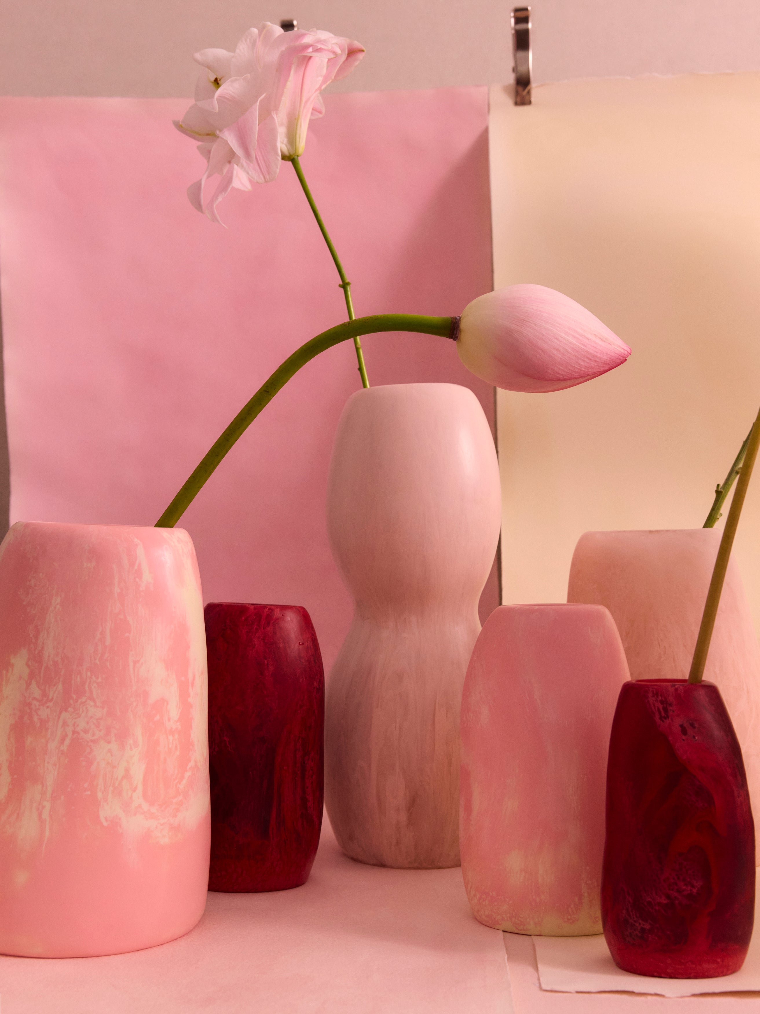 Variety of organic shaped pink resin vases with an assortment of flowers
