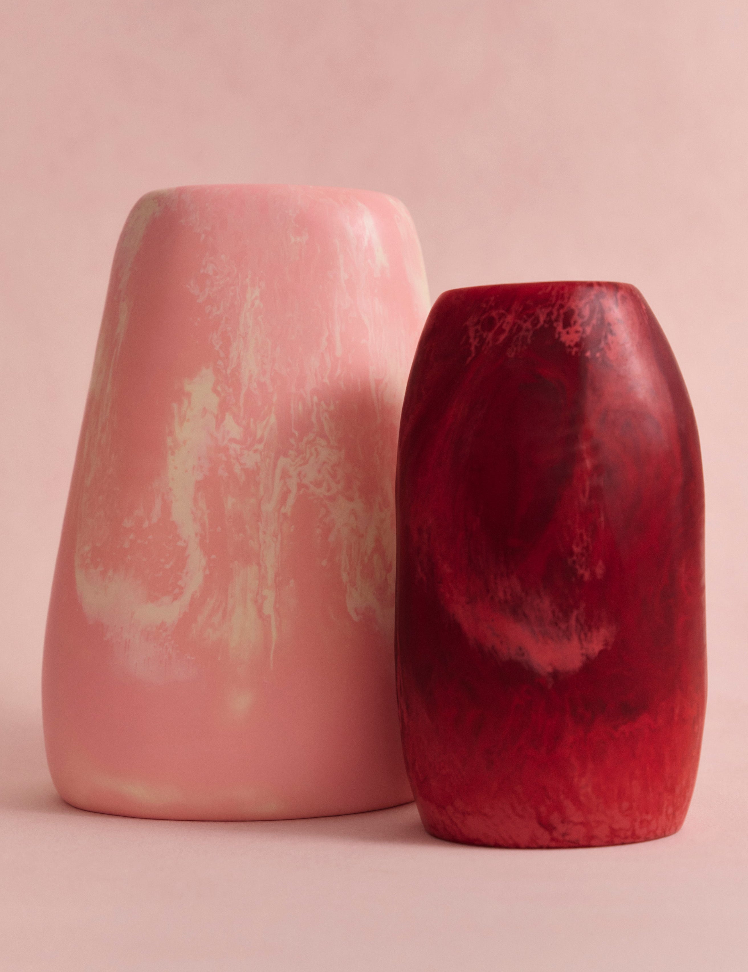 Two resin vases in pink and cream marbling, and deep pink on a light pink backdrop