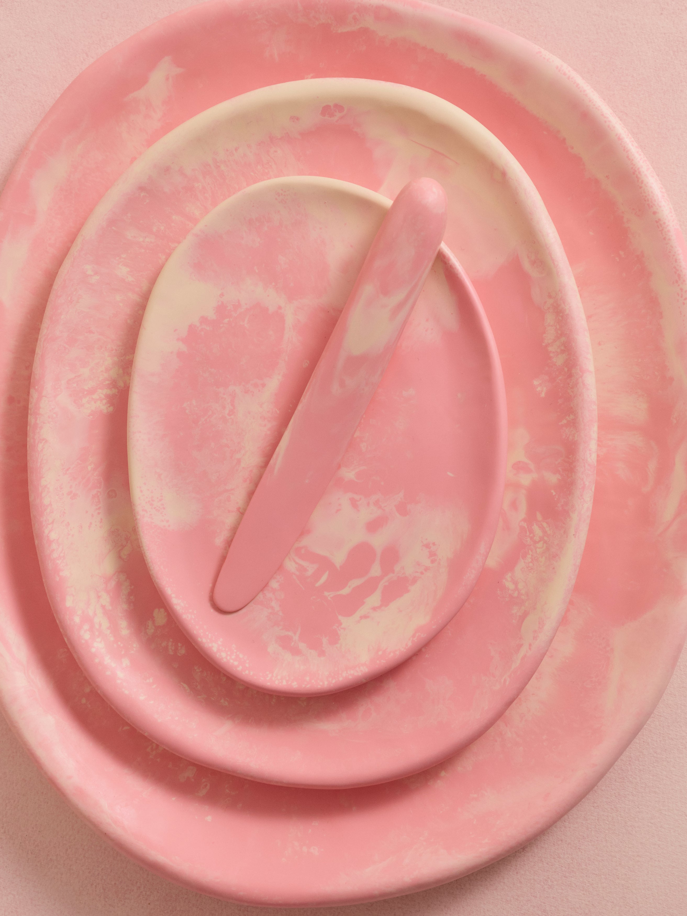 Stack of pink resin serving plates with a pink resin cheese knife atop