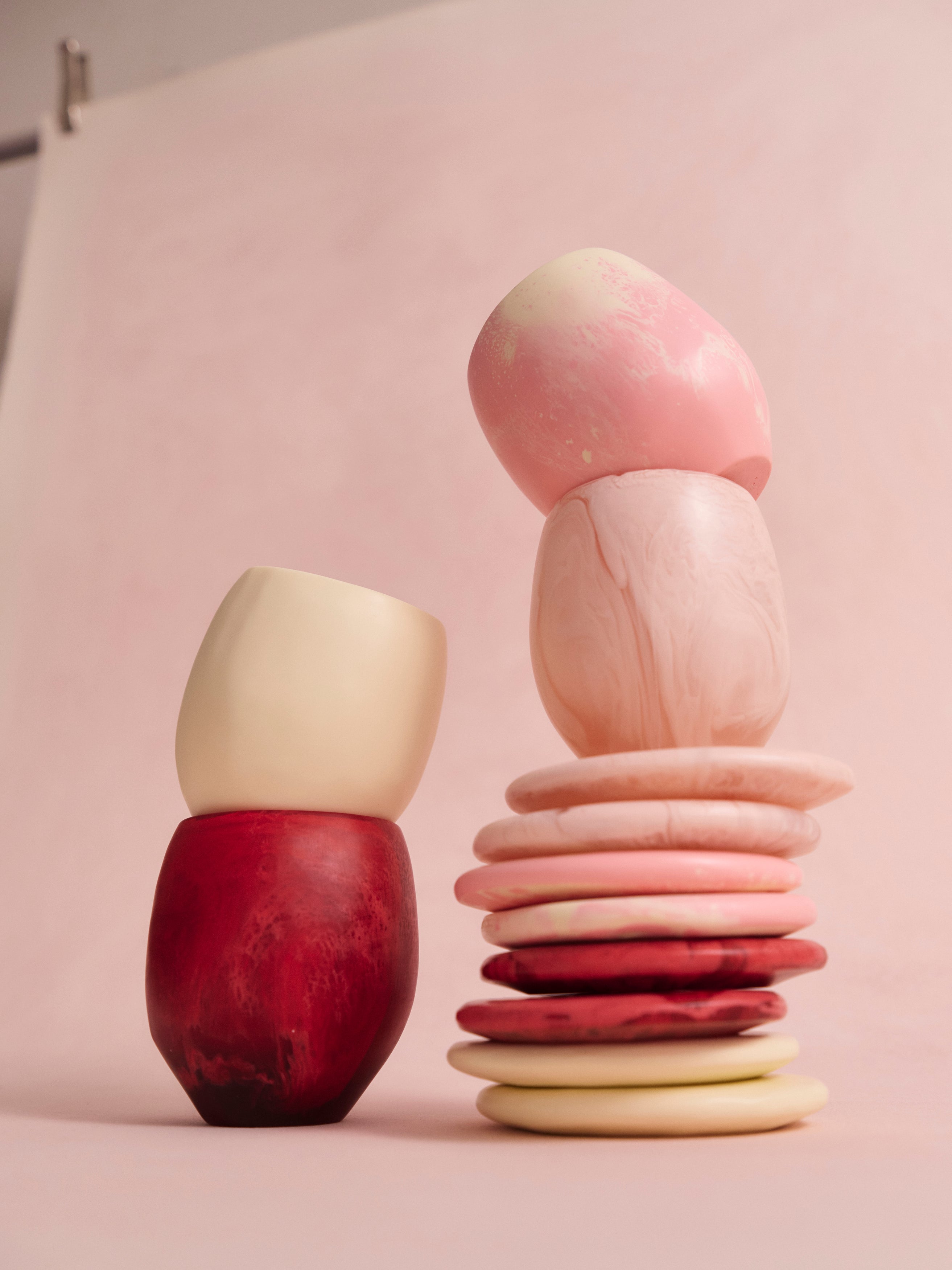 Stack of pink resin coasters accompanied by pink and cream resin cups alongside