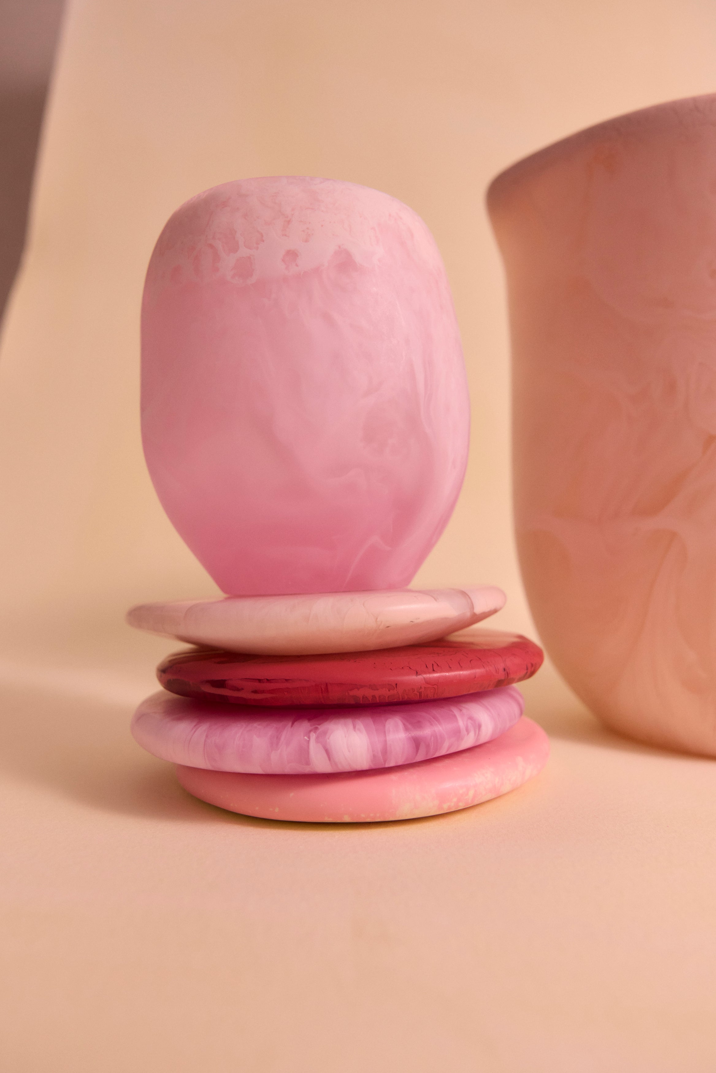 Stack of pink resin coasters accompanied by a pink resin cup atop