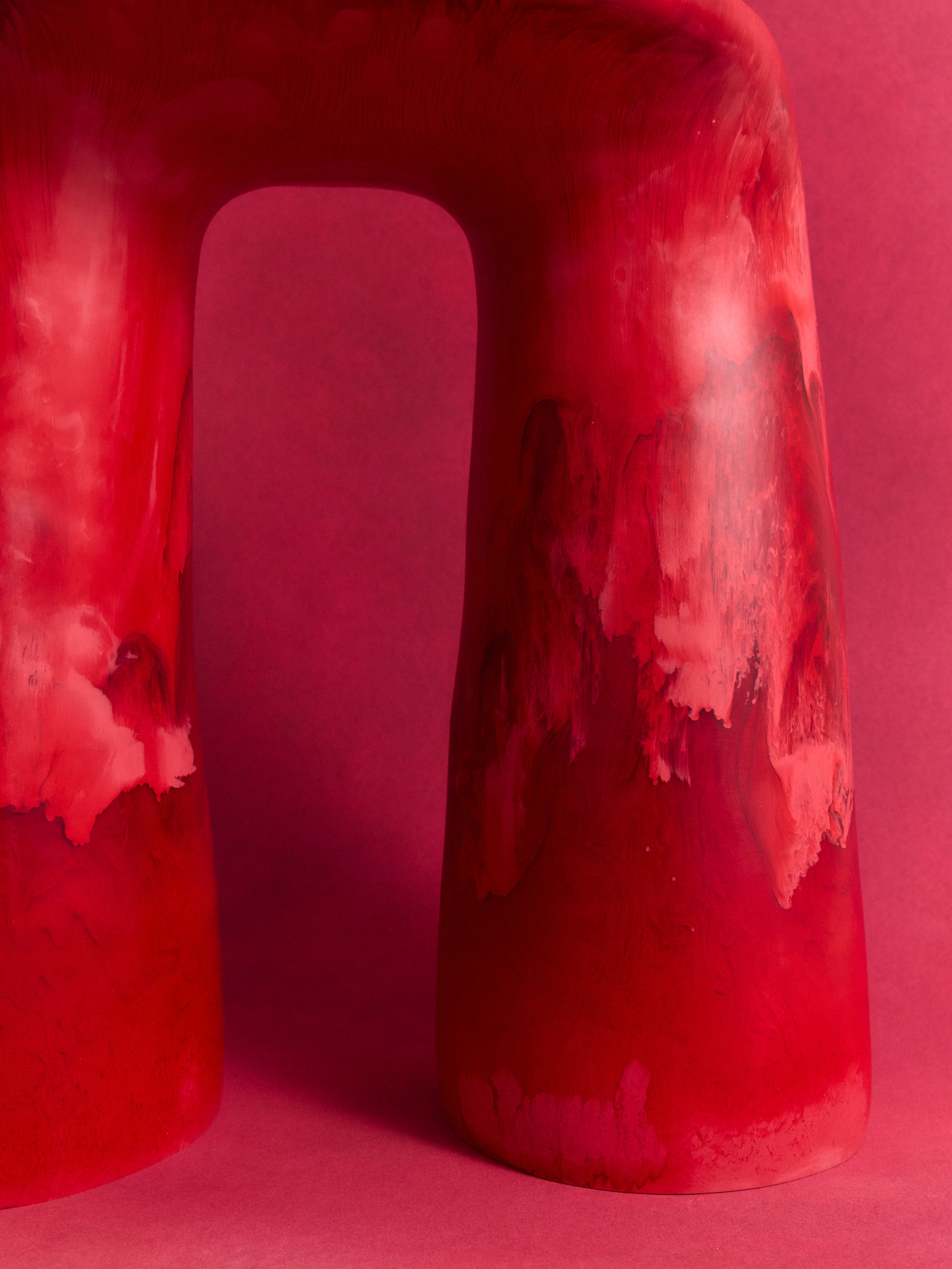 Close up of two legged deep pink resin table on a pink backdrop