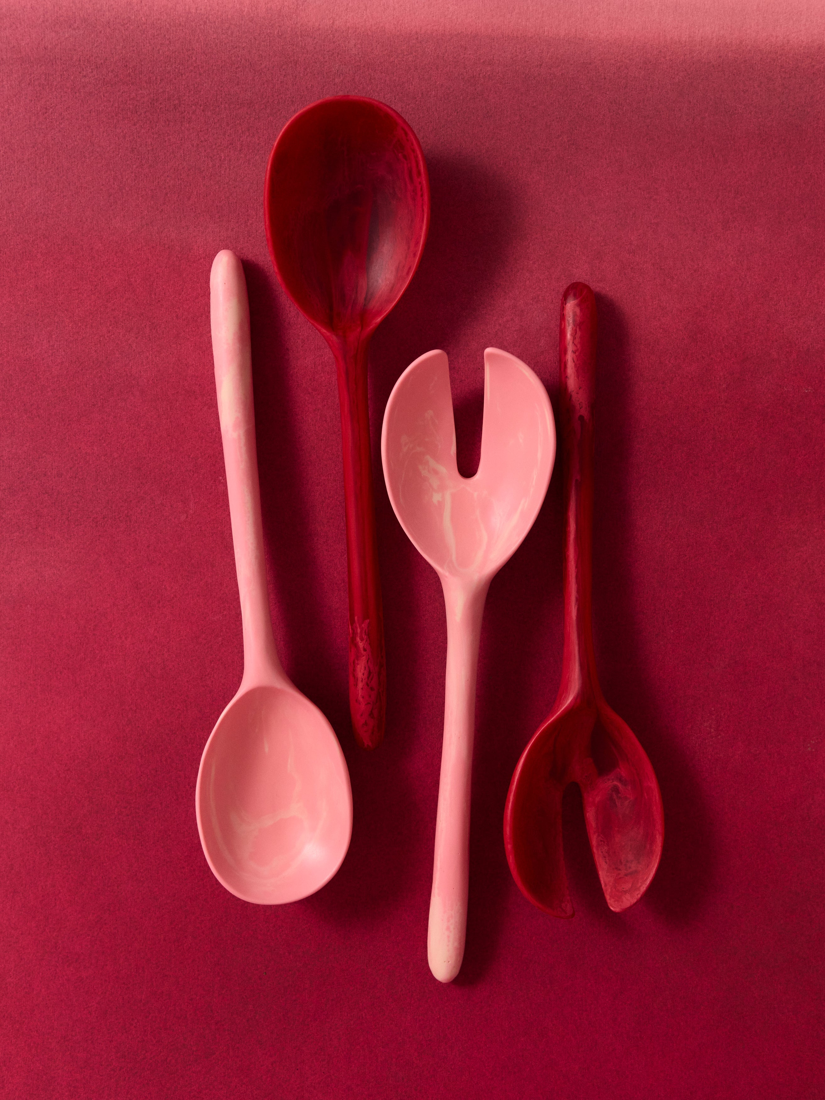 Pink and red resin serving spoons on a pink backdrop