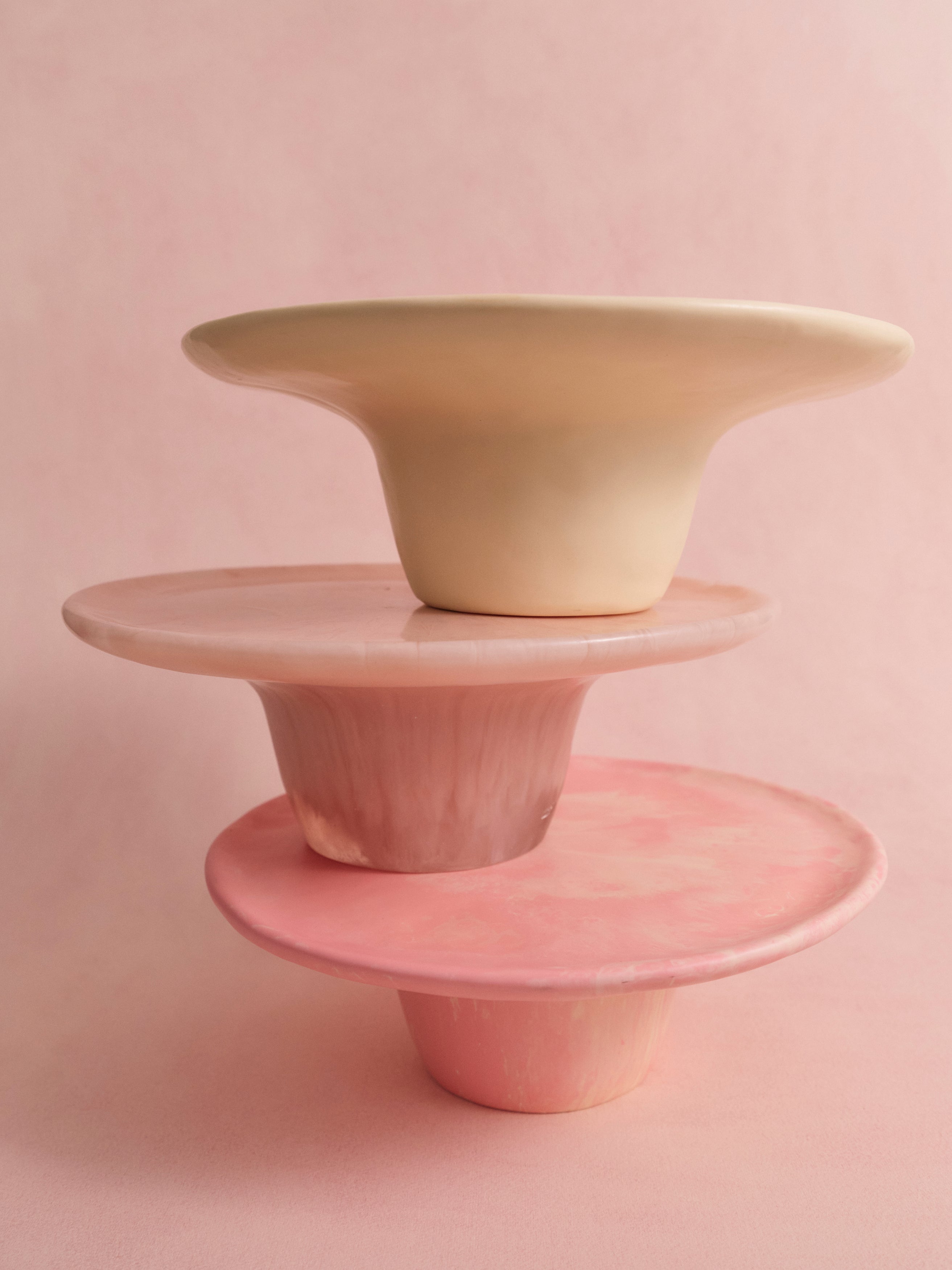 Three resin cake stands in pinks and cream stacked upon one another