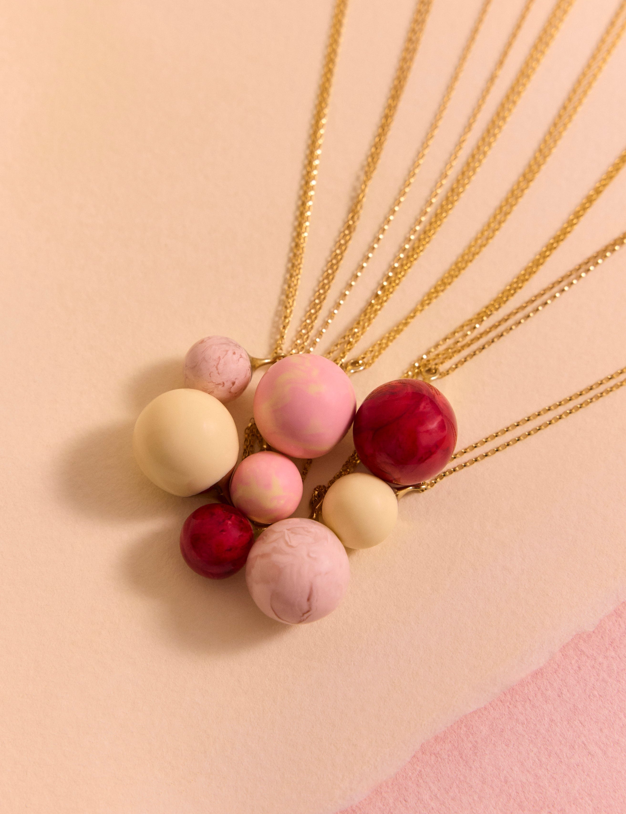 Pink resin ball necklaces layered on a pink background