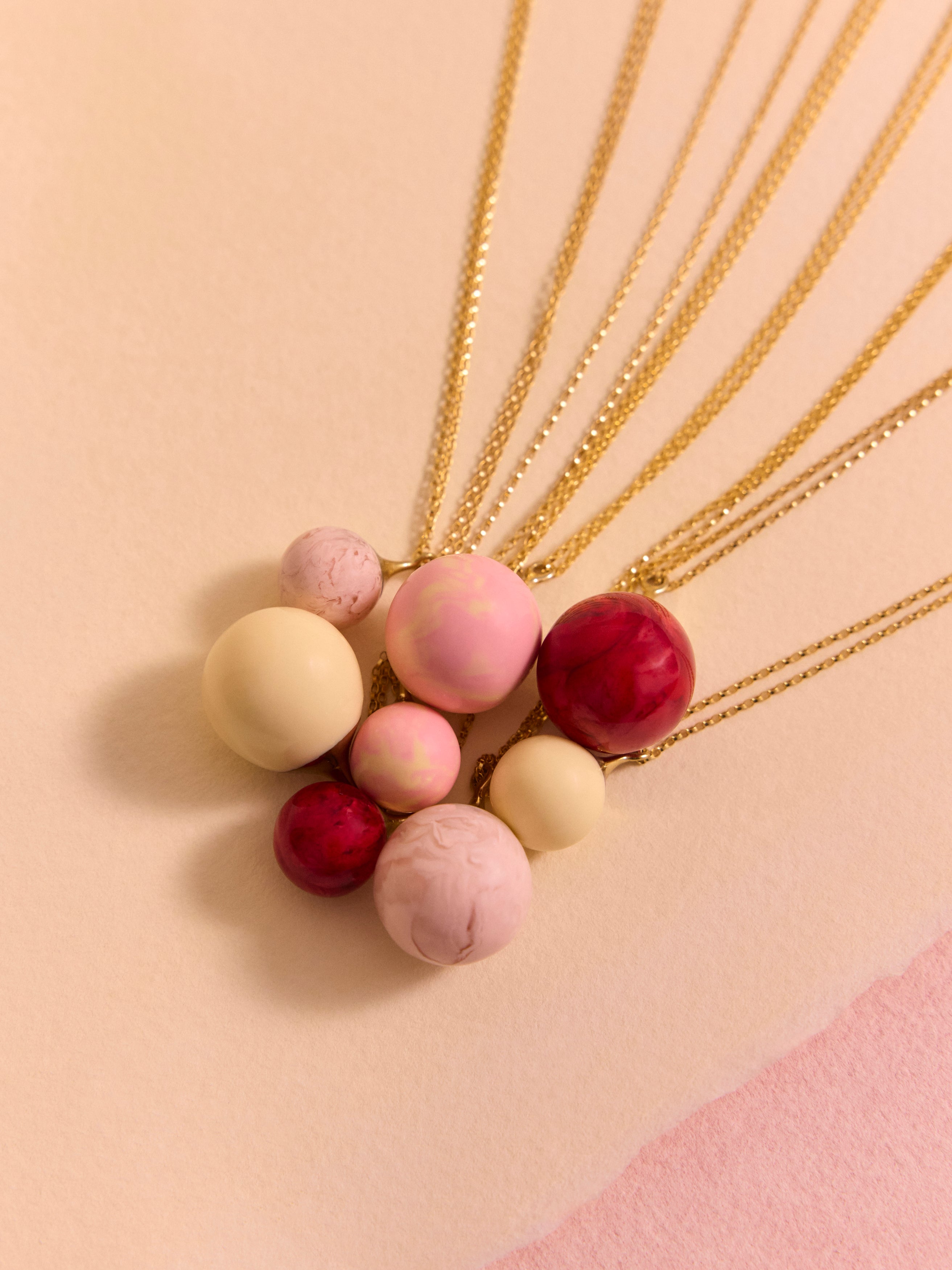 Pink resin ball necklaces layered on a pink background