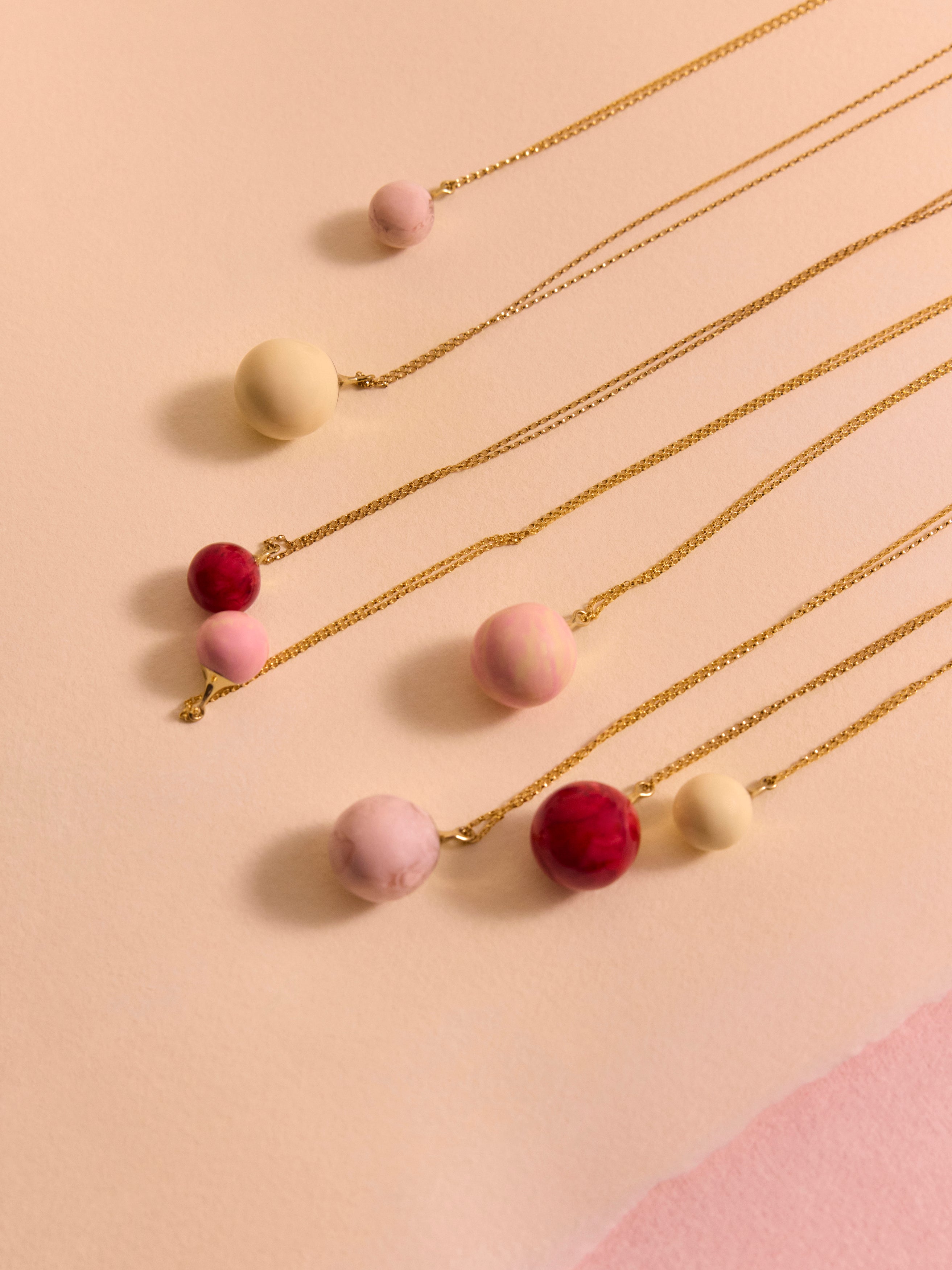 Pink resin ball necklaces layered on a pink background
